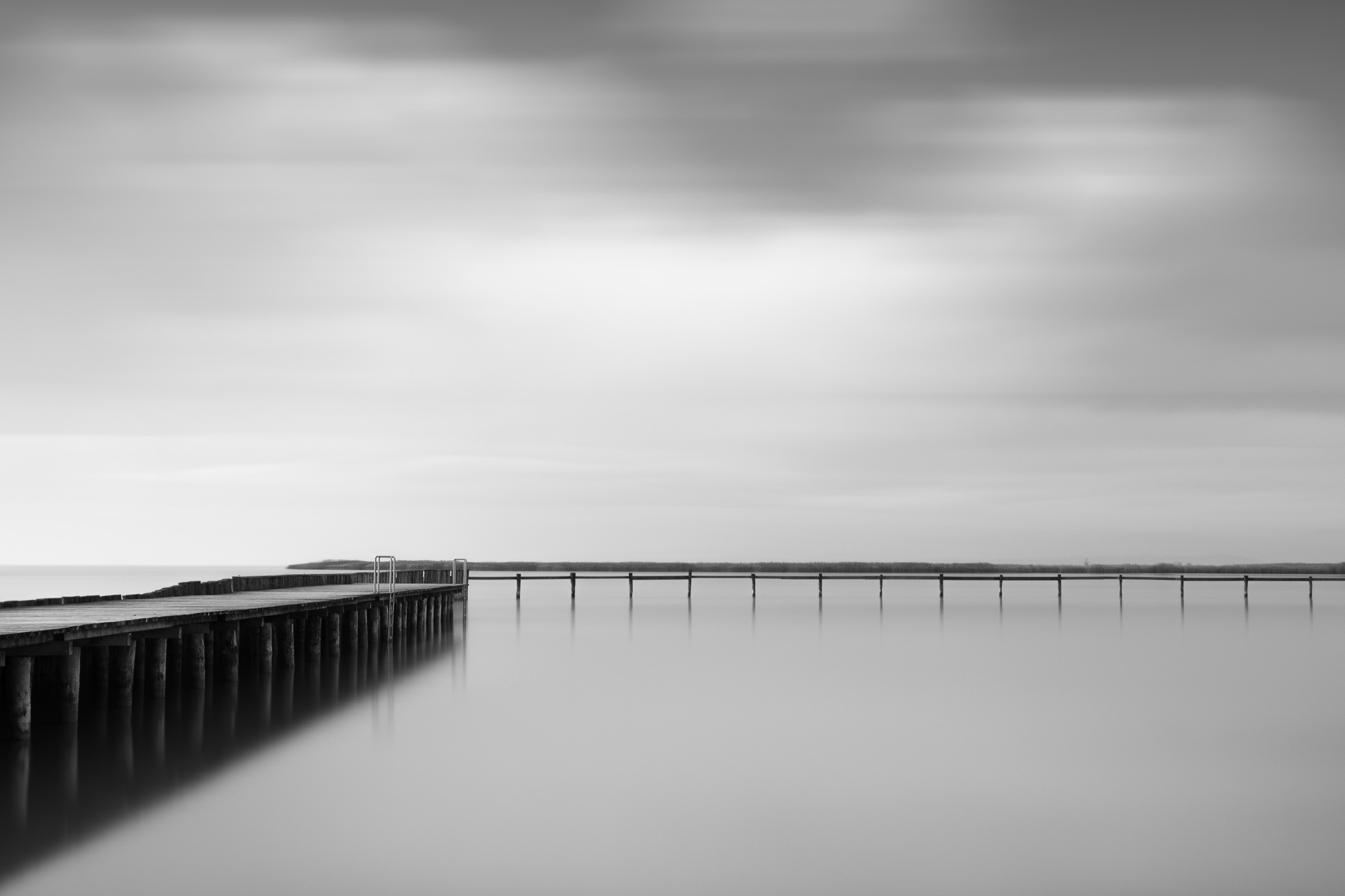 Wooden pier reaching into the sea under a cloudy sky